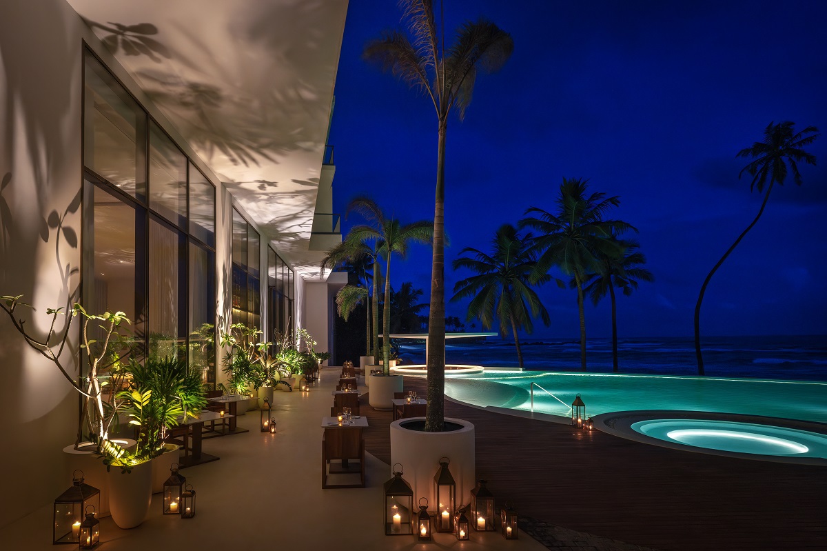 evening view of pool and palm trees with lights