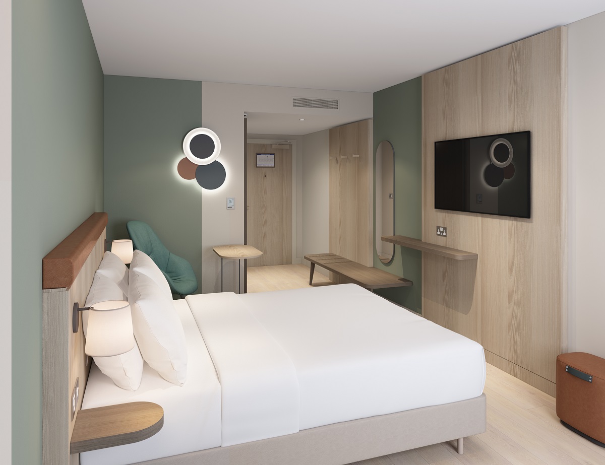 compact hotel bedroom with circular light and tv n the wall