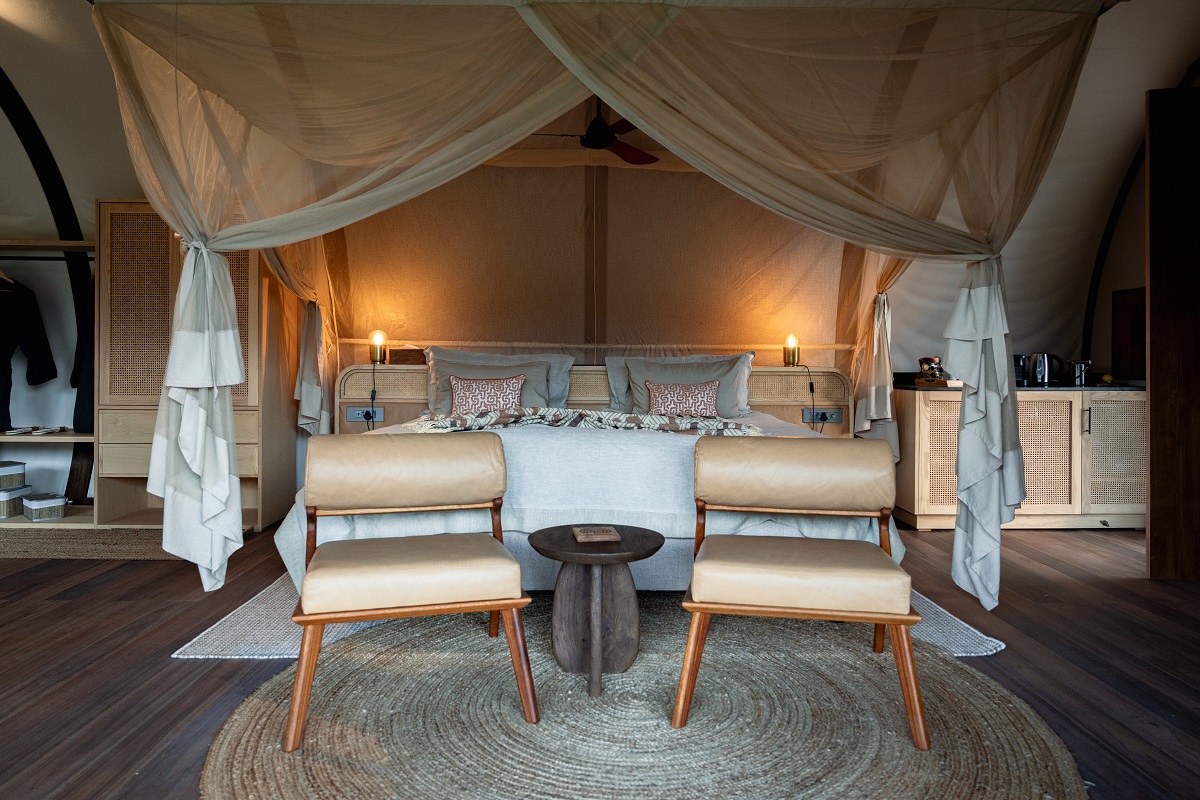 canopy draped four poster bed and chairs in bedroom of Luvhondo safari lodge