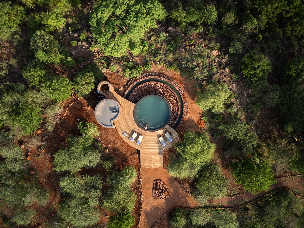 aerial view of round swimming pool surrounded by bushveld