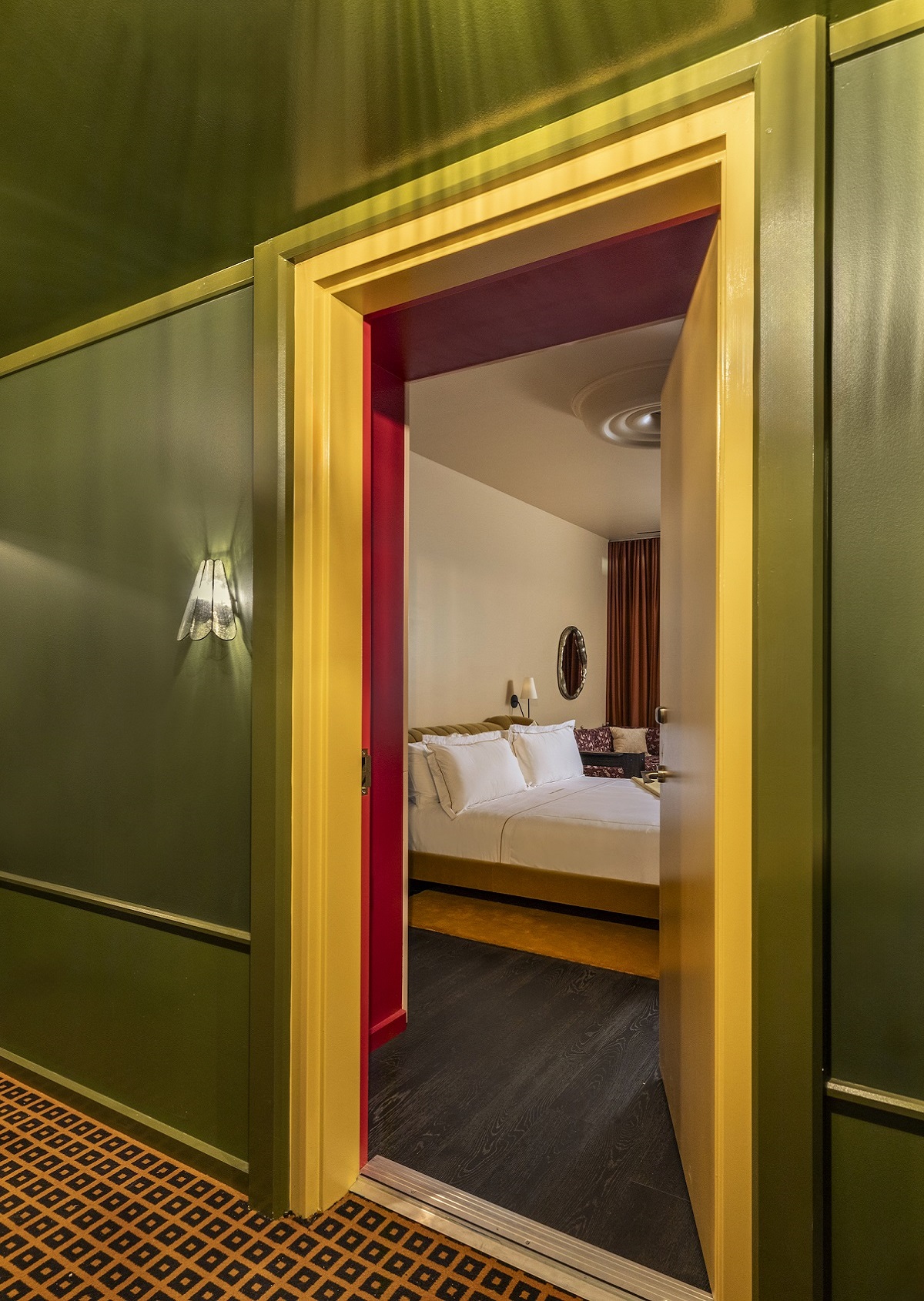 olive green corridor wall with yellow frame leading into bedroom with same colour accents