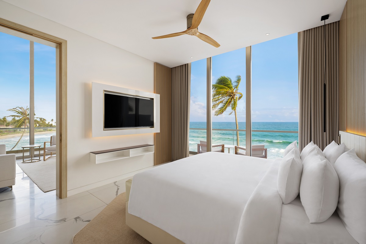 white bed lined, white furniture and floor in Radisson guestroom with view of Galle beach and sea