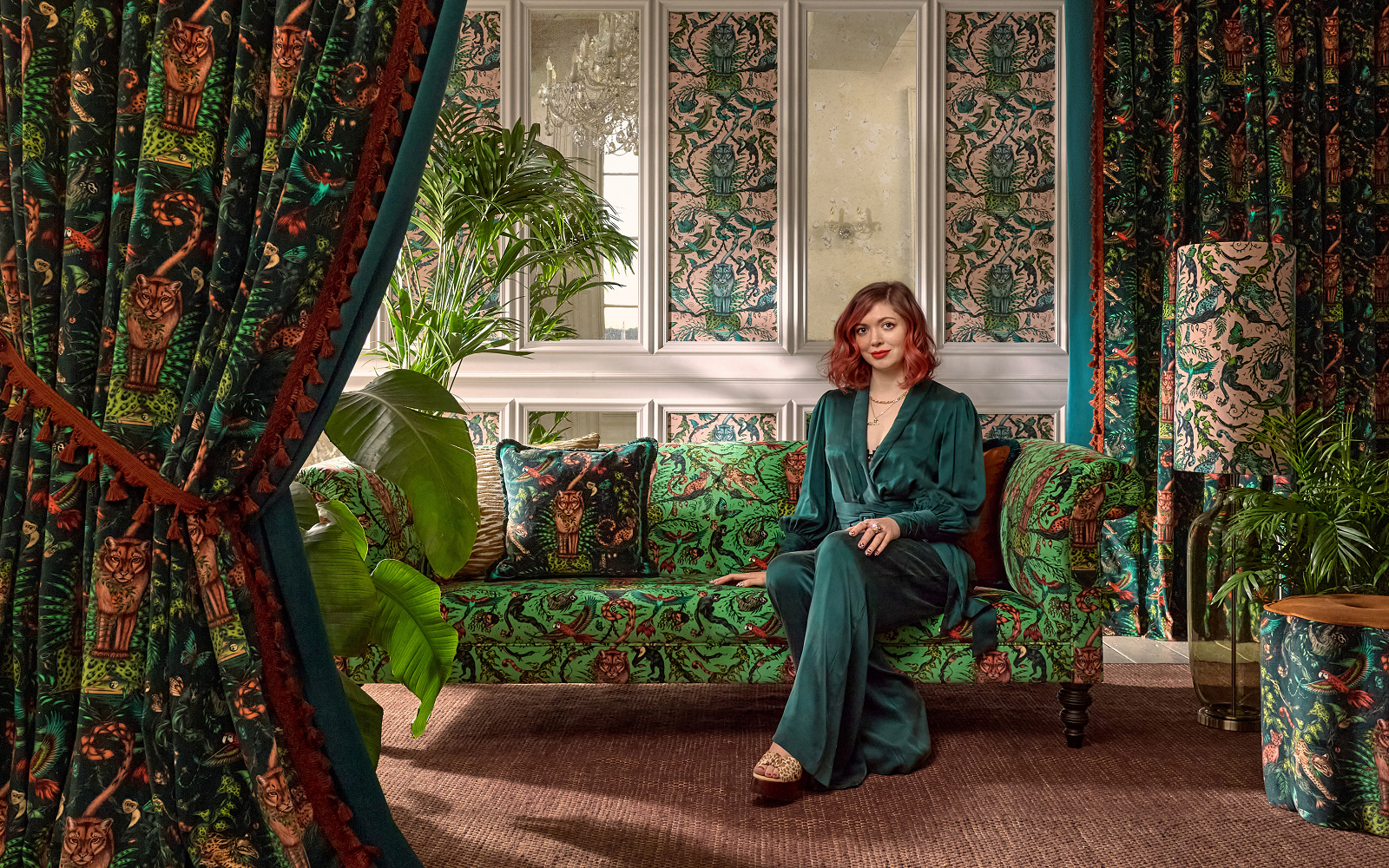 artist emma shipley on a green velvet couch with patterned drapes from Mythica collection