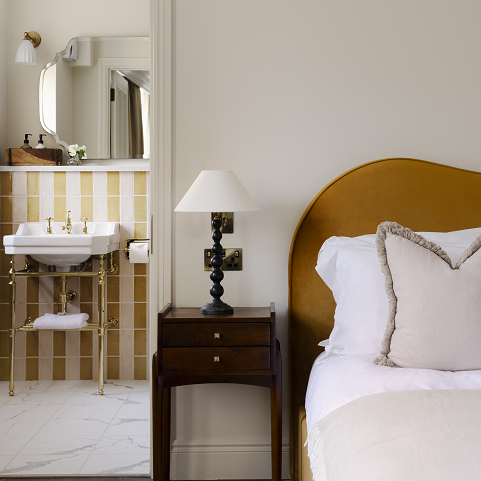 yellow and cream striped bathroom tiles and yellow velvet headboard in hotel guestroom