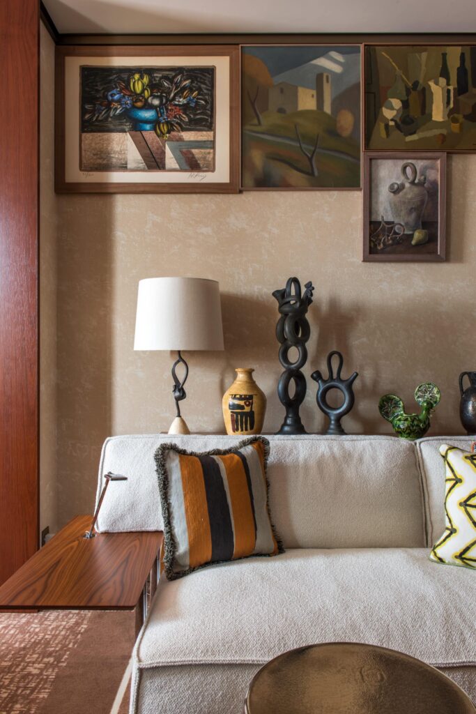 Lounge area of a suite in the Brach Madrid, with a white sofa and folk like shelving and artworks behind