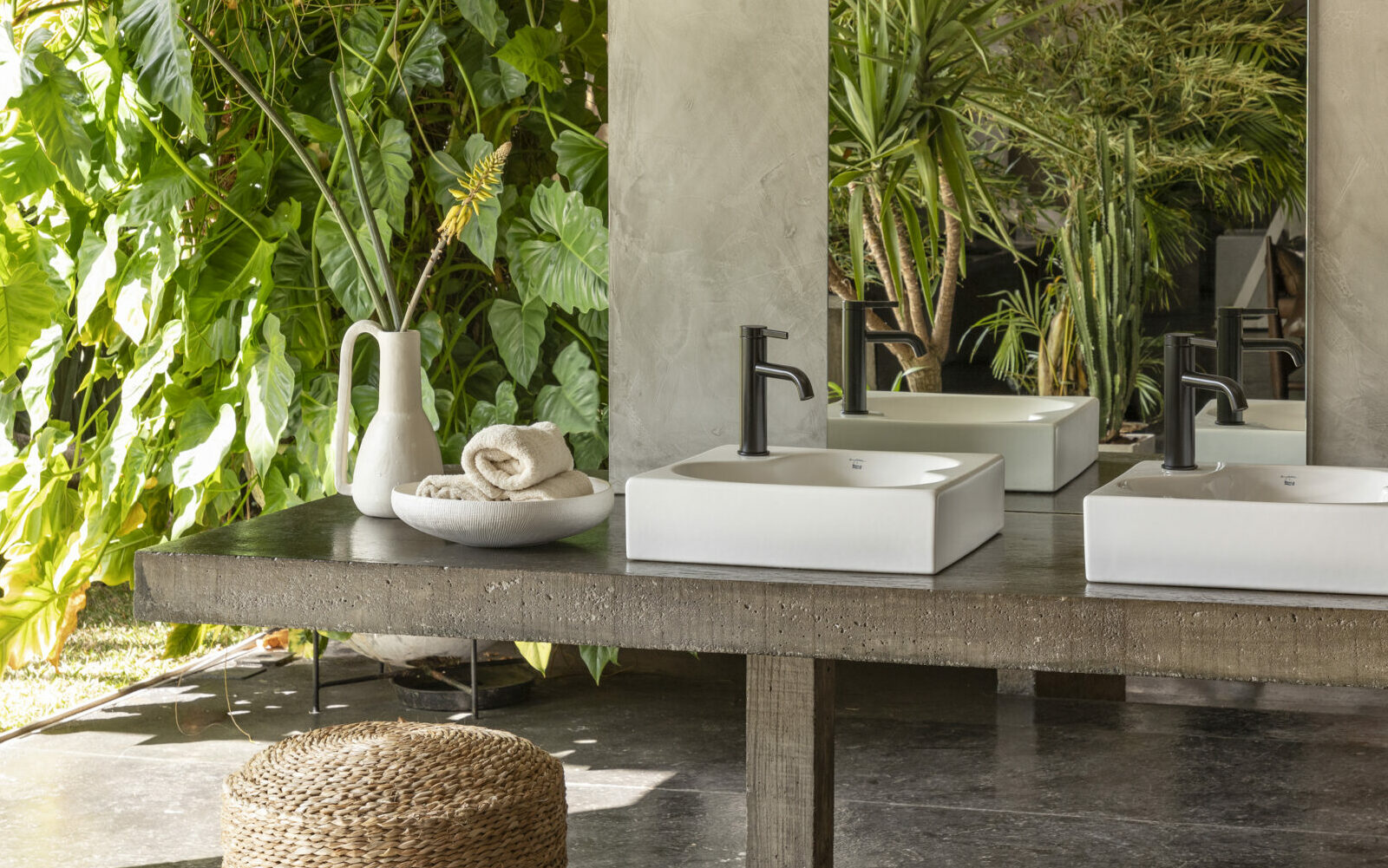 Double Ohtake basins in outdoor bathroom area, greenery surrounds