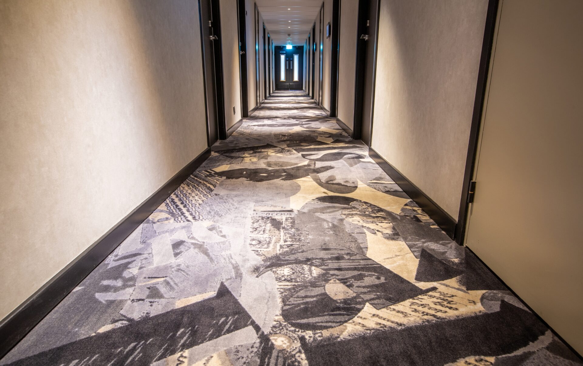 Long hotel corridor, white walls and grey patterned carpet