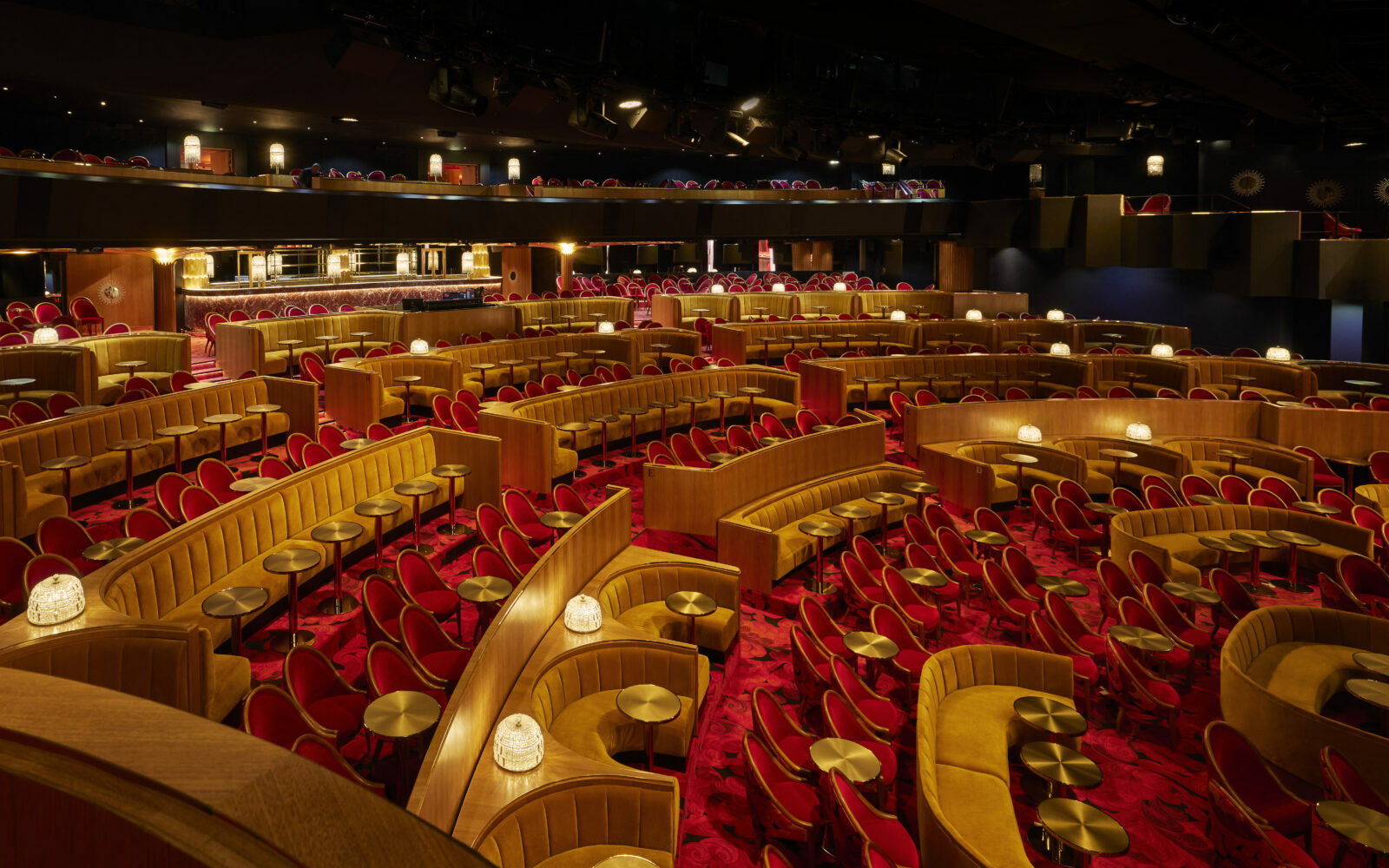 Gold, theatre style seating in a Parisian cabaret hall, with geometric red patterned carpets by Ege Carpets