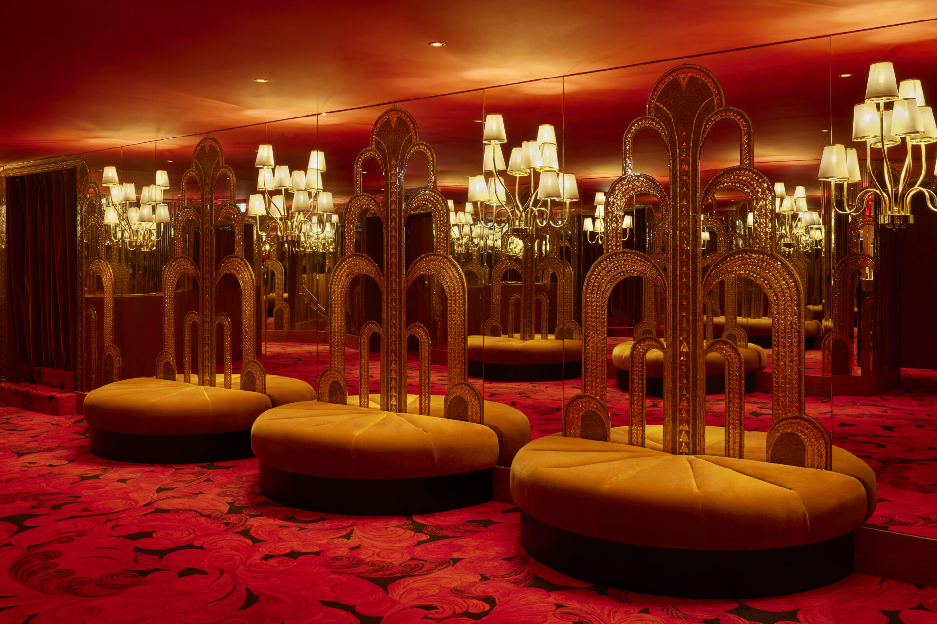 Mirrored wall with gold and velvet banquette seating infront. 