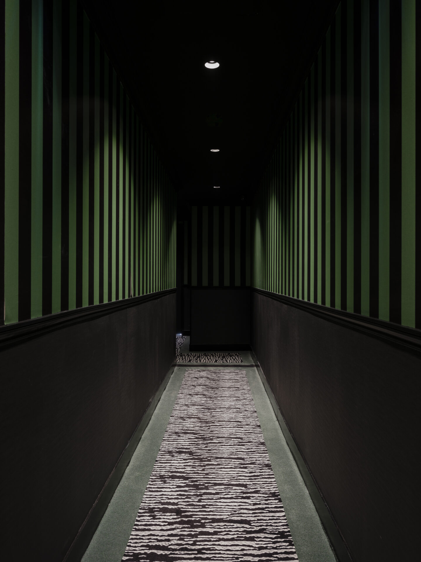 Green walled corridor of hotel, with patterned carpet