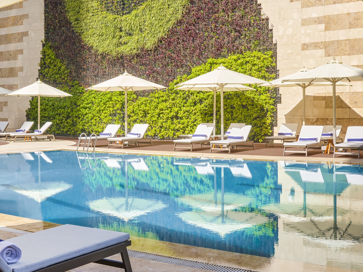 swimming pool with umbrellas and planted wall at Hilton Cairo Nile Maadi