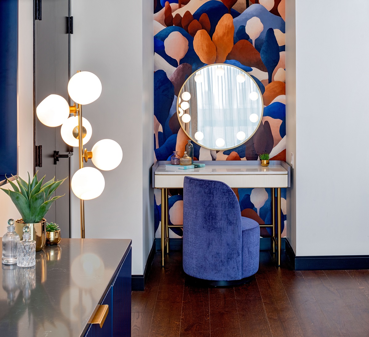 blue vanity chair in front of round mirror on patterned wall 