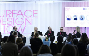 five panellists sit in front of pink and white concertina paper backdrop, on stage at Surface Design Show 2025