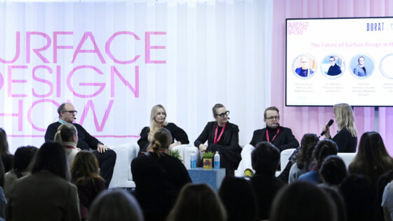 five panellists sit in front of pink and white concertina paper backdrop, on stage at Surface Design Show 2025