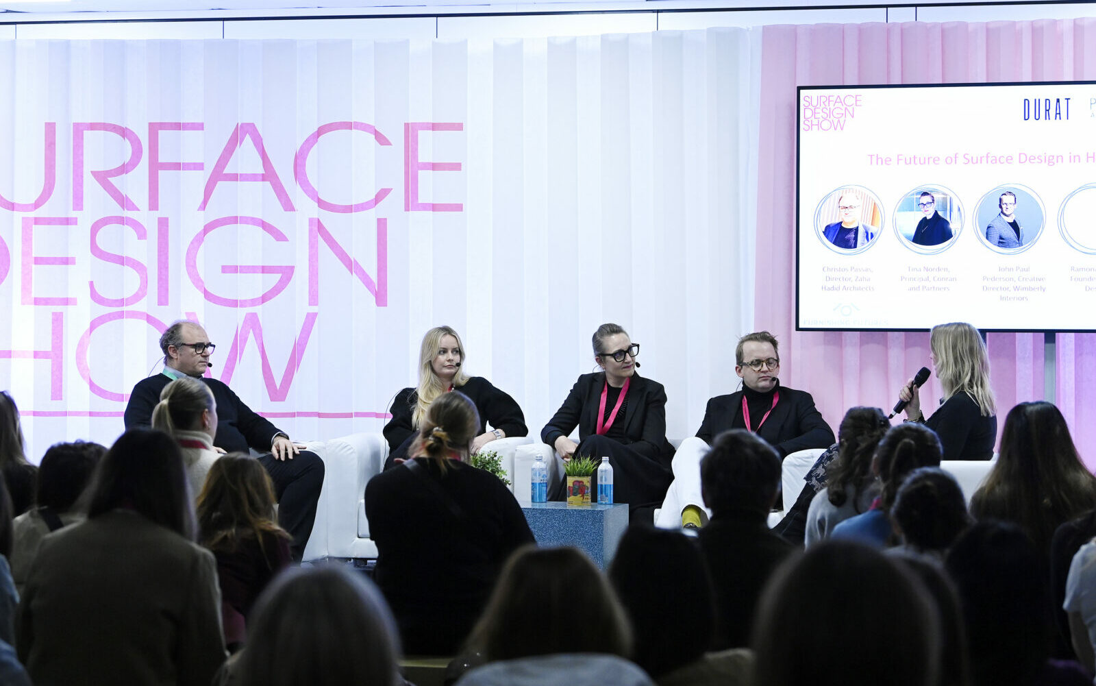 five panellists sit in front of pink and white concertina paper backdrop, on stage at Surface Design Show 2025