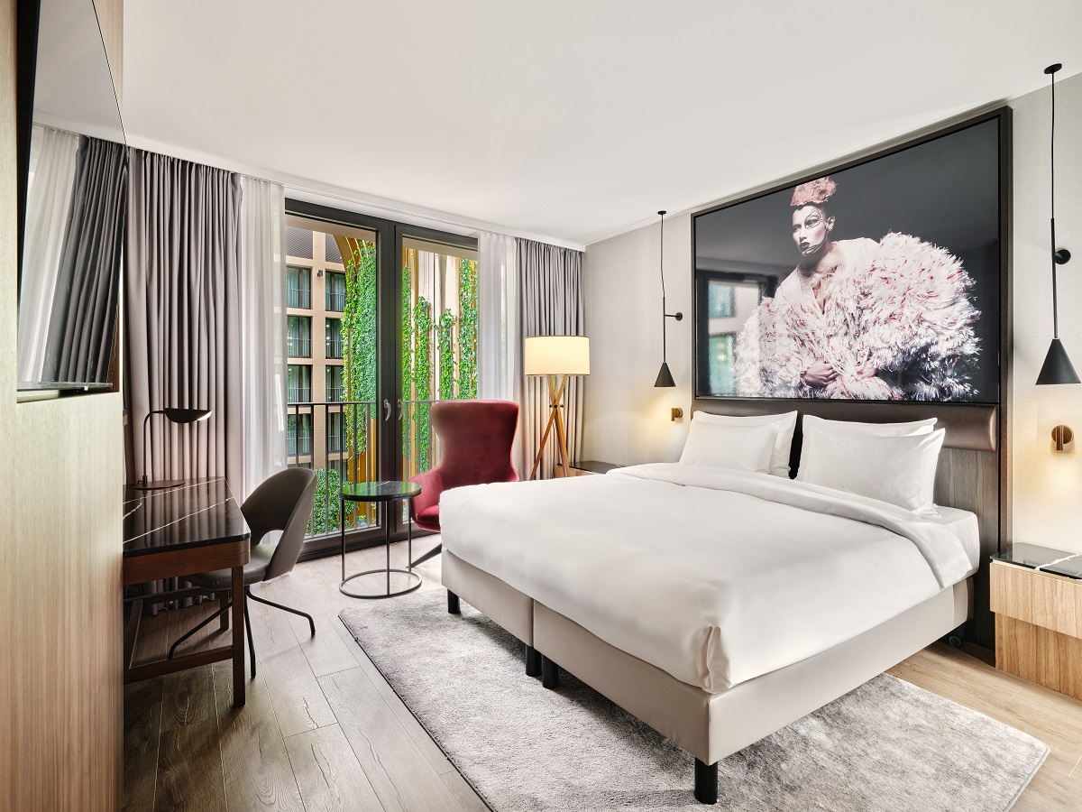 guestroom with view over central atrium and plants with photographic art above the bed