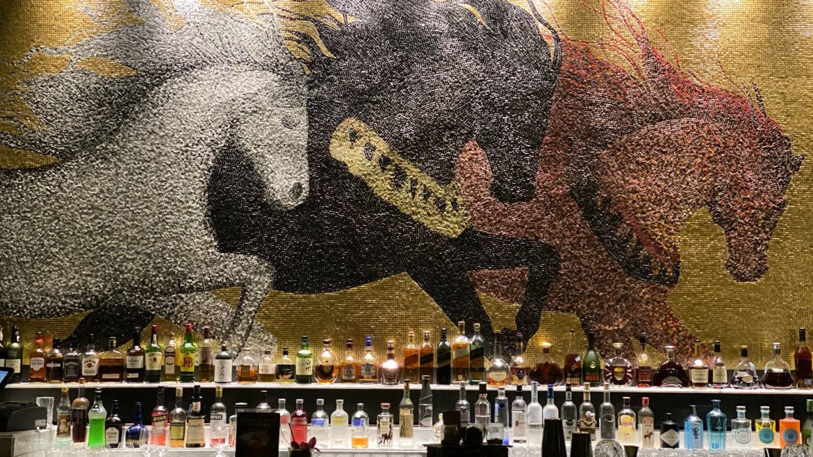 mosaic tile mural of horses behind bar