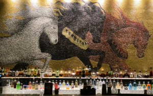 mosaic tile mural of horses behind bar