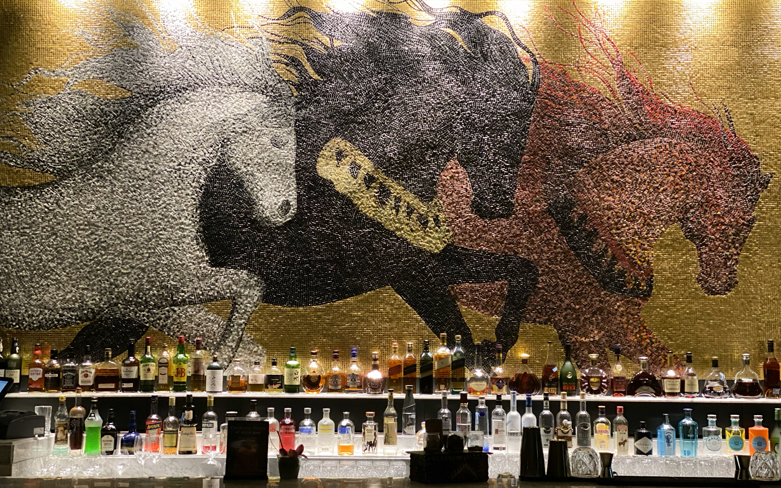 mosaic tile mural of horses behind bar