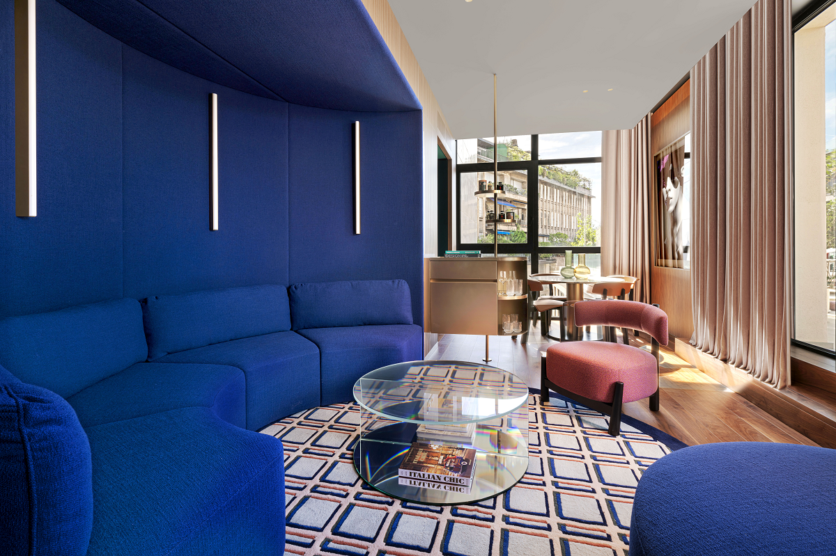 drenched blue walls and furniture with clear coffee table on patterned carpet