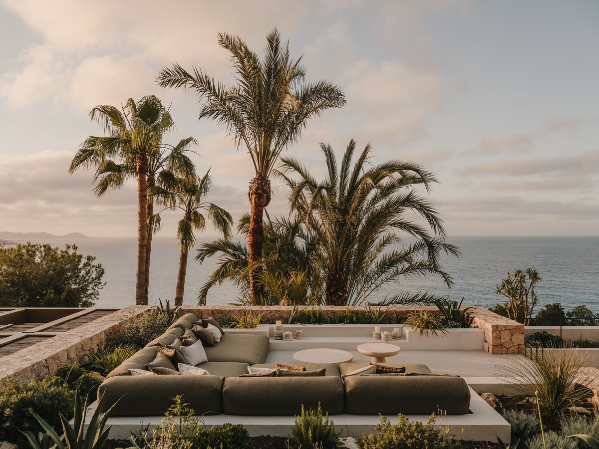 outdoor sunken seating with palm trees and sea view in ibiza