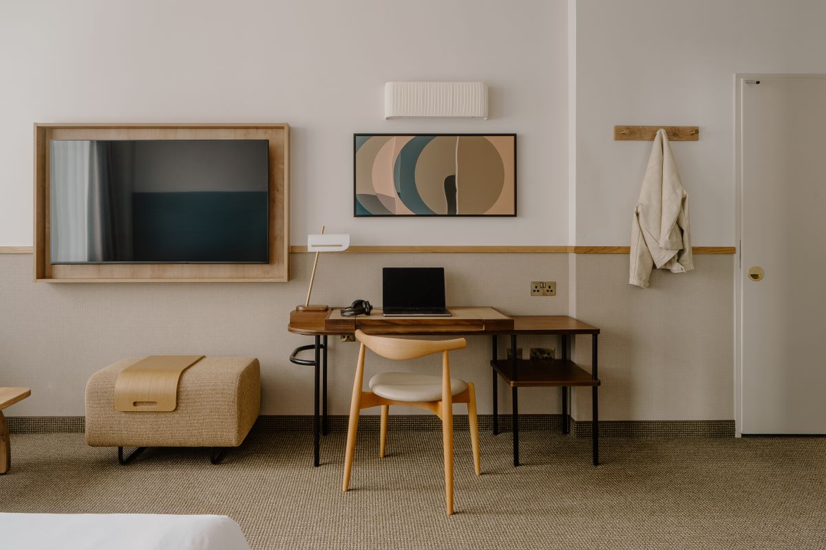 Wall in guestroom of the Gracechurch Street Hotel by Club Quarters, showing a desk, pouffe, and tv mounted on the wall