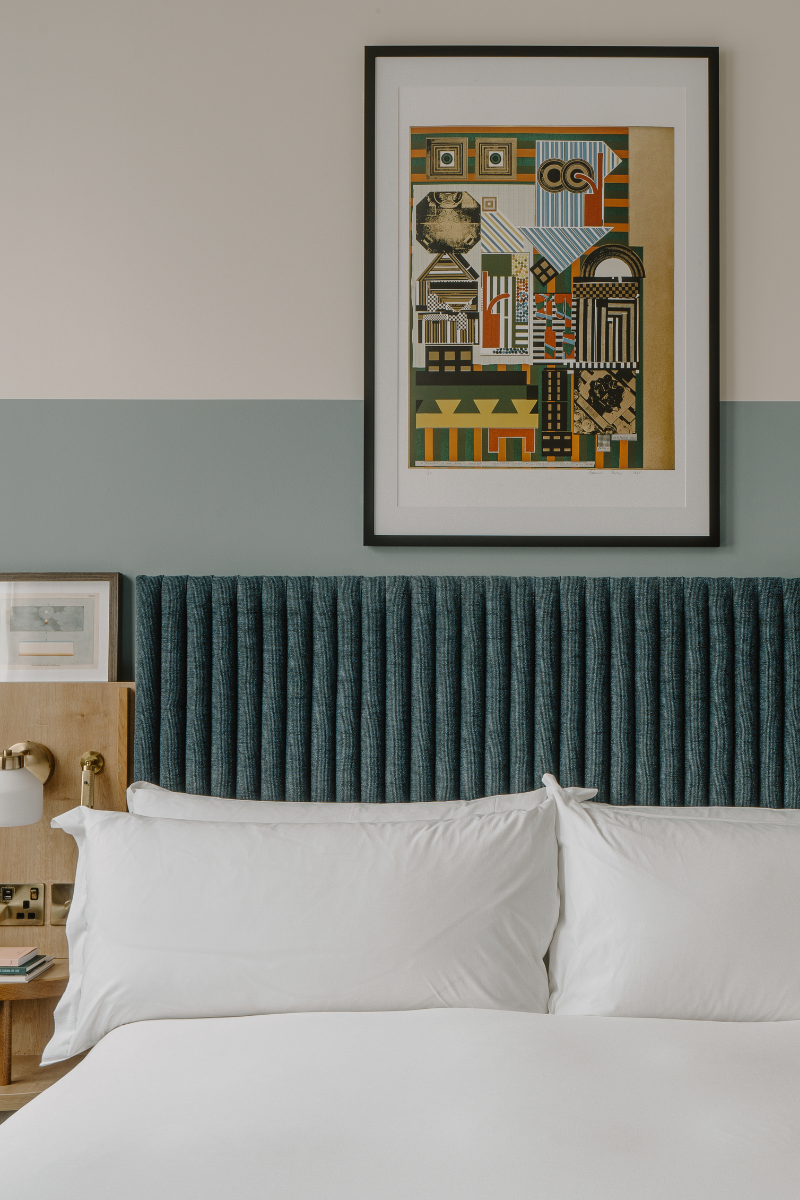 Close up shot of bed, headboard and painting on wall above