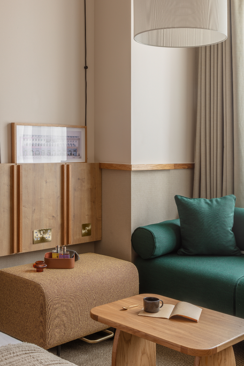 Close up shot of corner of guestroom with green armchair, and woodern banquette