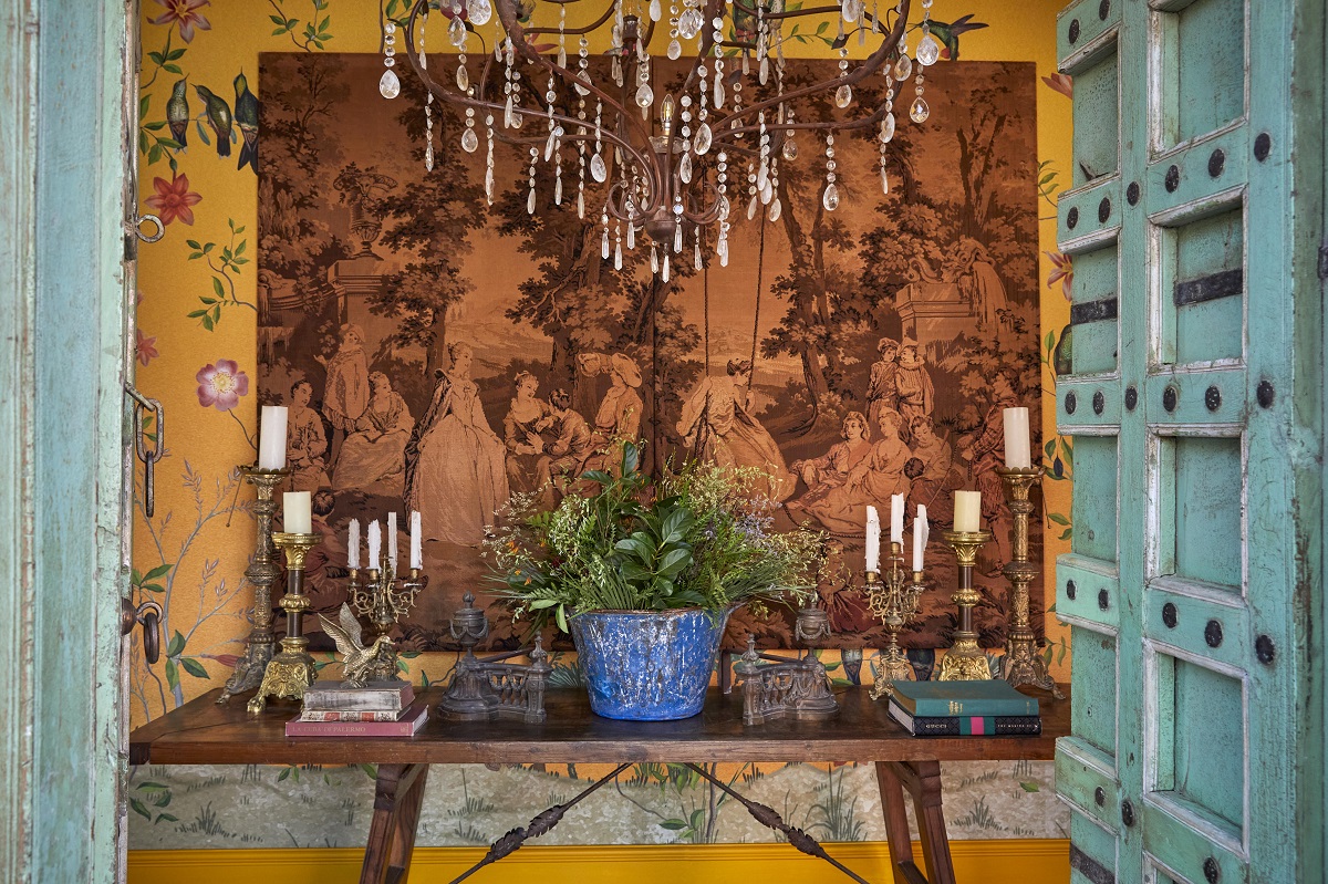 blue front door opening onto yellow walls with pattern and tapestry and chandeliers