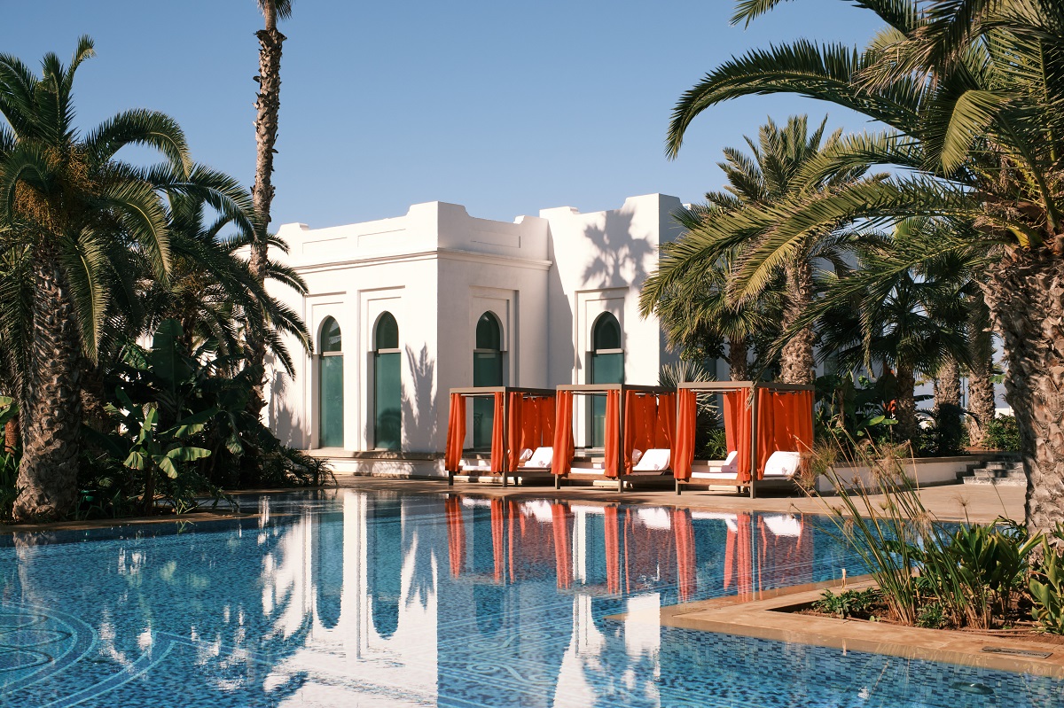 orange draped cabanas alongside pool and palm trees in Four Seasons Rabat