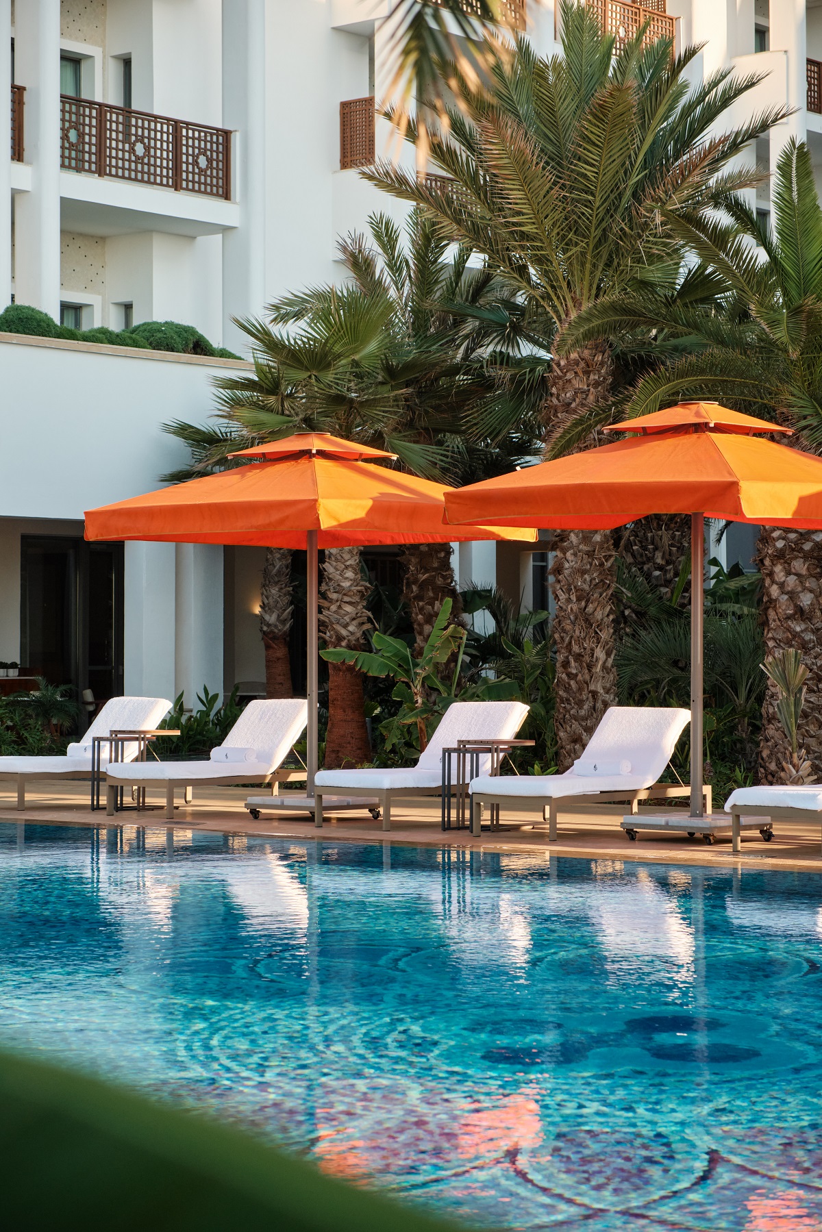 white sun loungers and orange umbrellas next to the pool at Four Seasons Rabat