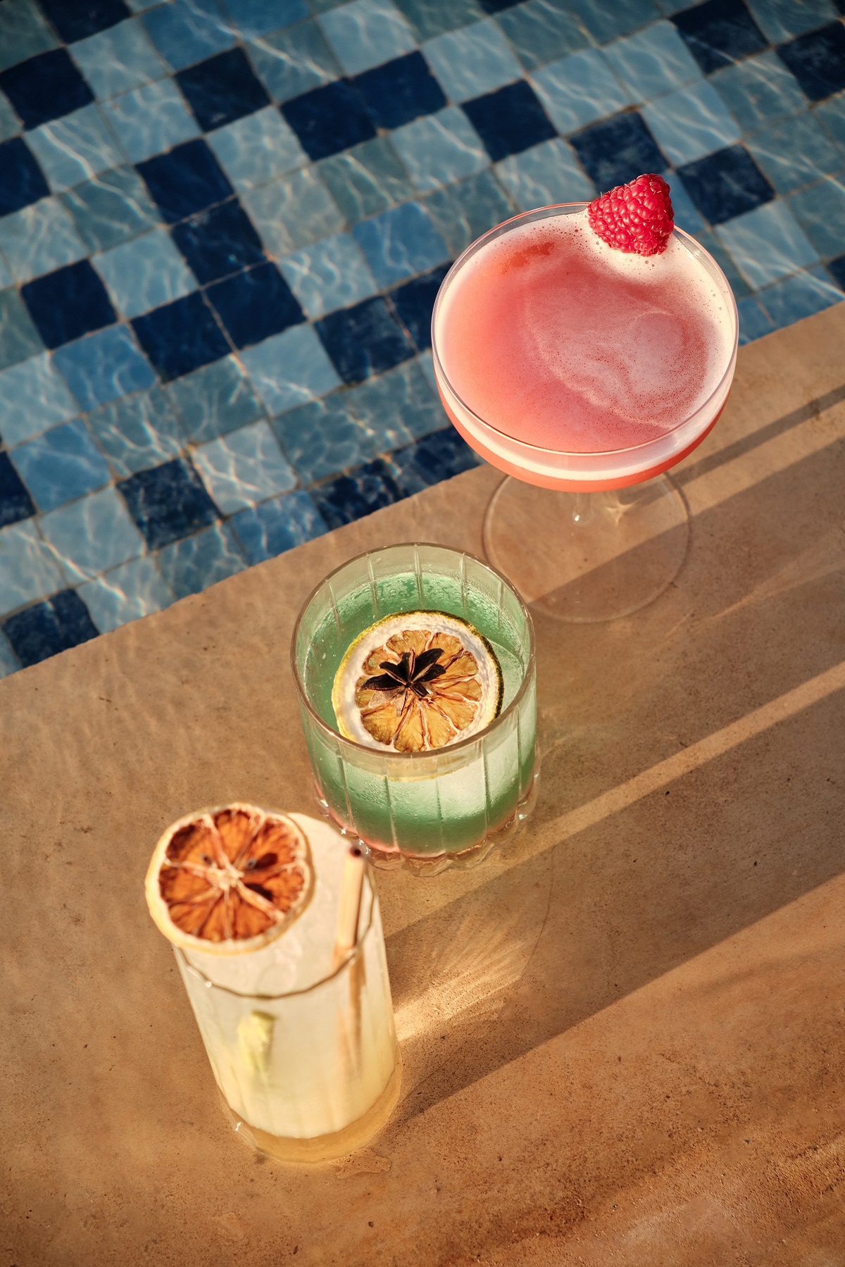three cocktails next to a pool
