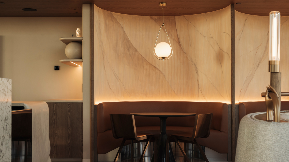 Warm neutral tone restaurant space at Movenpick Brussells Airport by WeWantMore. Banquette seating area is lit by hanging circular ceiling pendant
