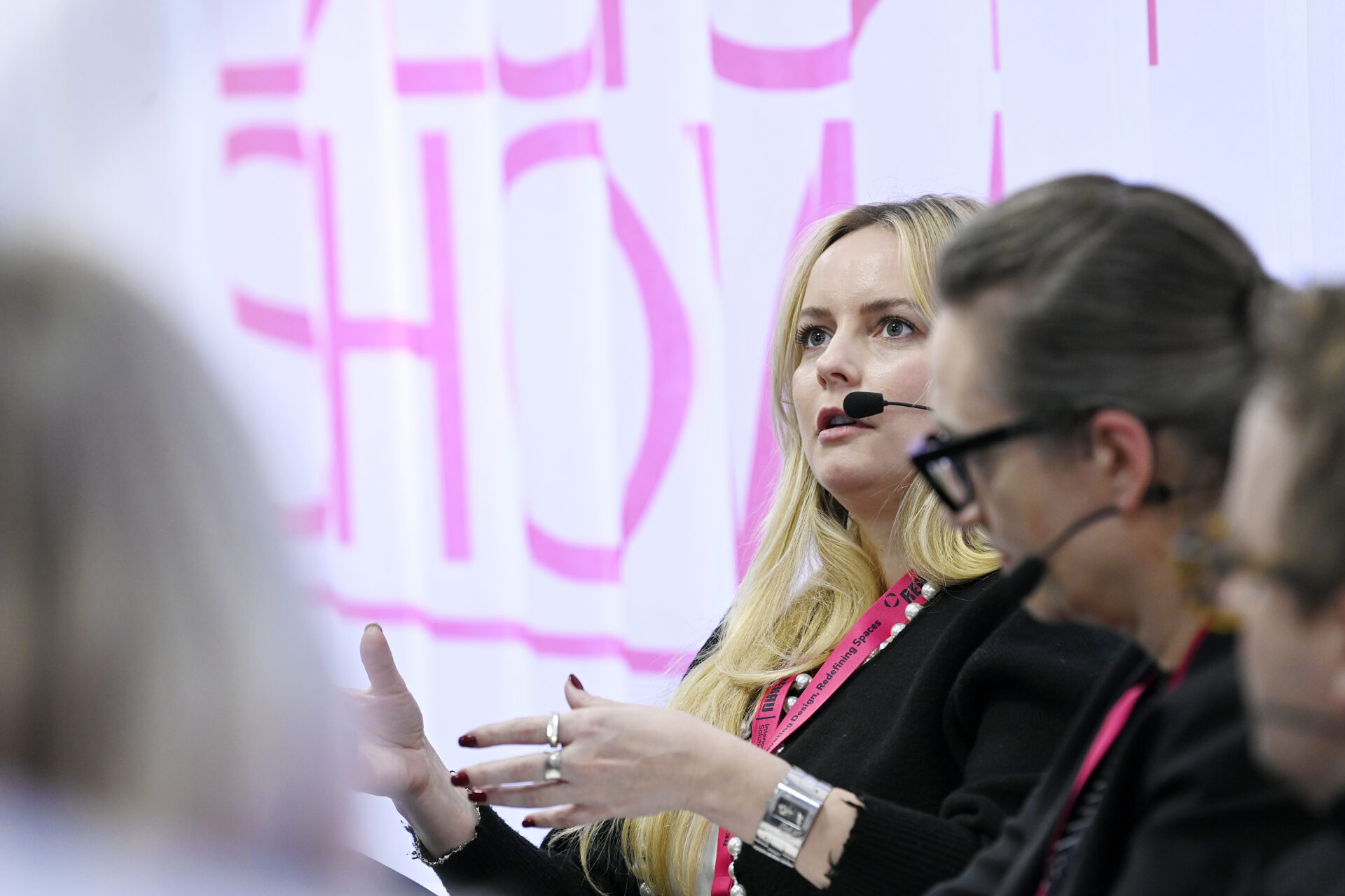 Close up shot of panellist mid flow of conversation at Surface Design Show, with pink show text name on screen behind