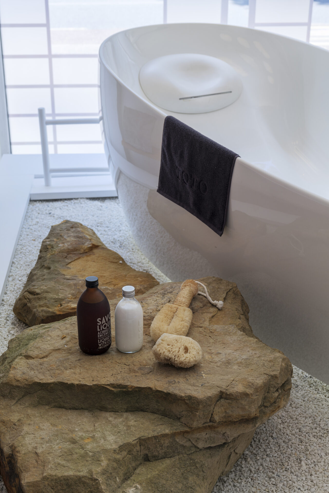 TOTO flotation bath with natural stones acting as a toiletries shelf