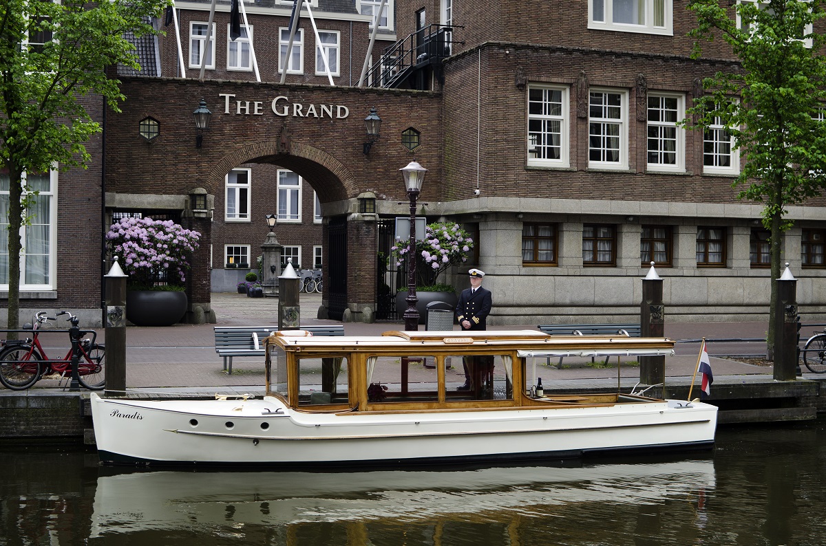 boat on Amsterdam canal in front of Sofitel Legend The Grand Amsterdam