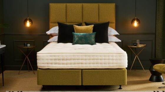 Chartreuse bed and headboard with Hypnos mattress, in dark coloured bedroom with low lighting from pendants either side of bed