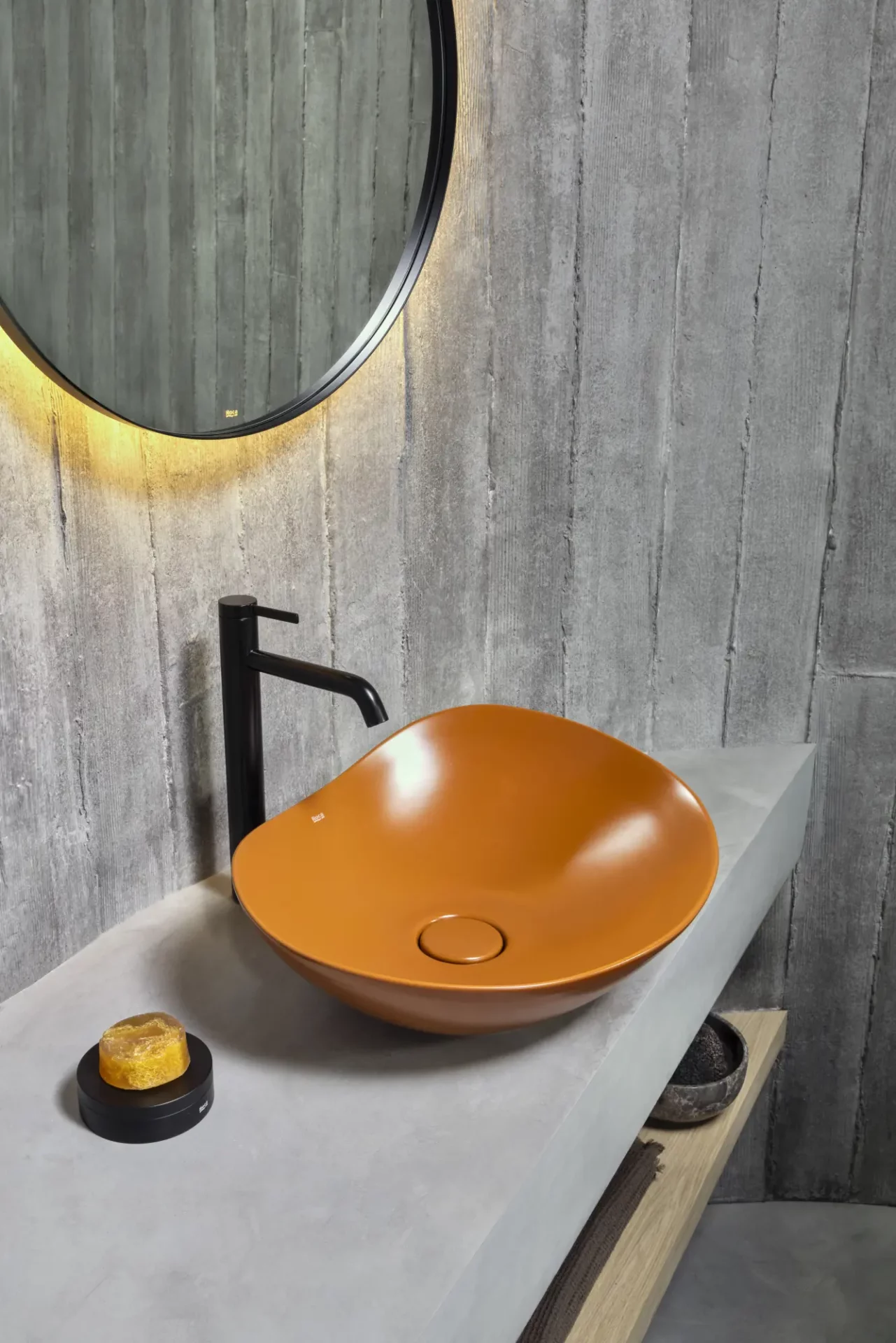 Orange organic sink basin with black tap in grey wood panelled bathroom