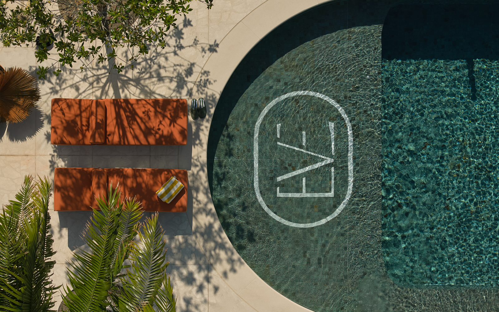 birds eye view of pool with The EVE logo and orange sunlounger