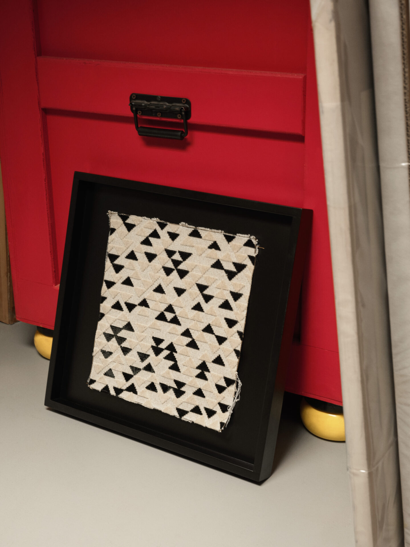 Black and white geometric woven fabric set against red backdrop