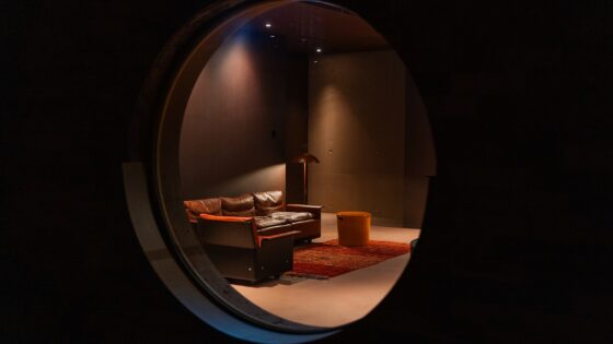 porthole window in Hotel Borsari looking on to minimalist furniture under a spotlight