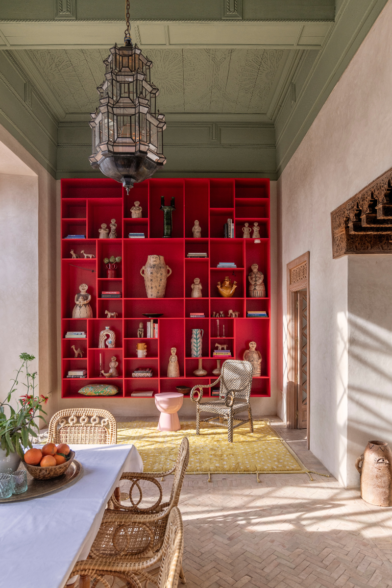 Light and airy dining area with red floor to ceiling bookshelf on far wall