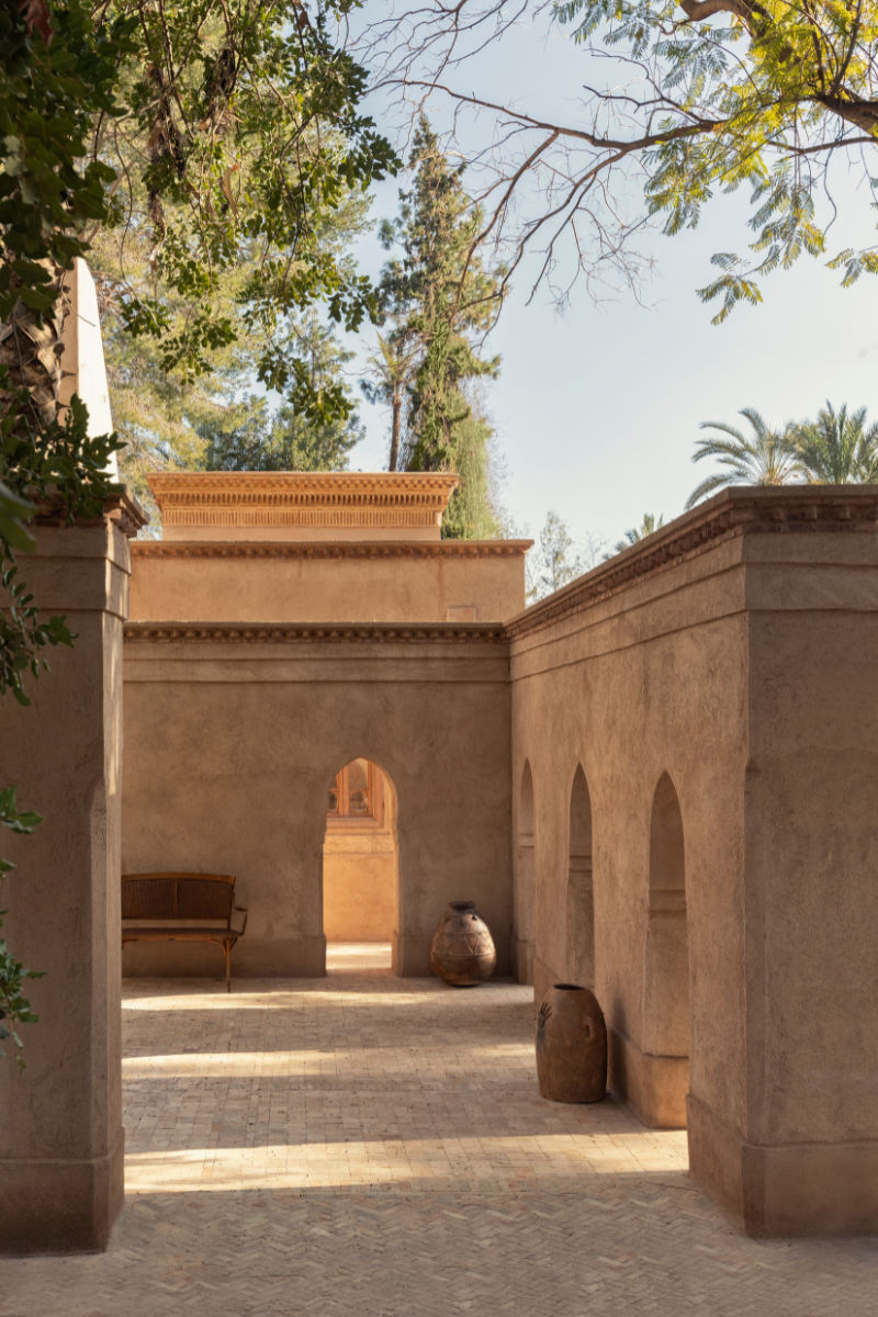 Shot of exterior of Jnane Rumi, Marrakech, showing wall of archways and building framed by ancient fruit trees