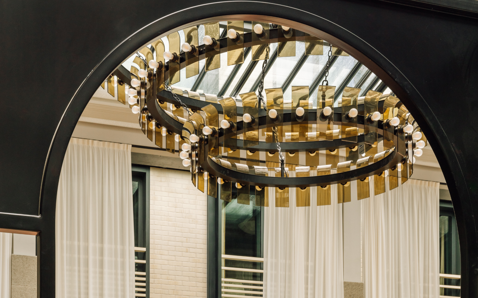 Le Jardin de Verre three-tiered chandelier hanging from glass ceiling, shot through archway