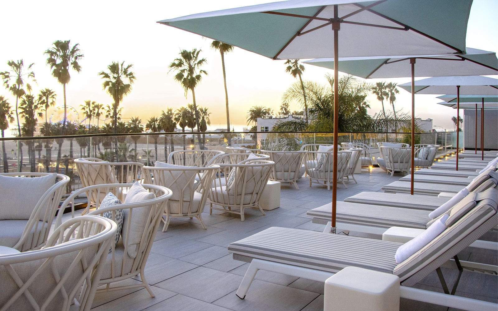 palm trees and umbrellas on the terrace at sunset at Regent Santa Monica Beach