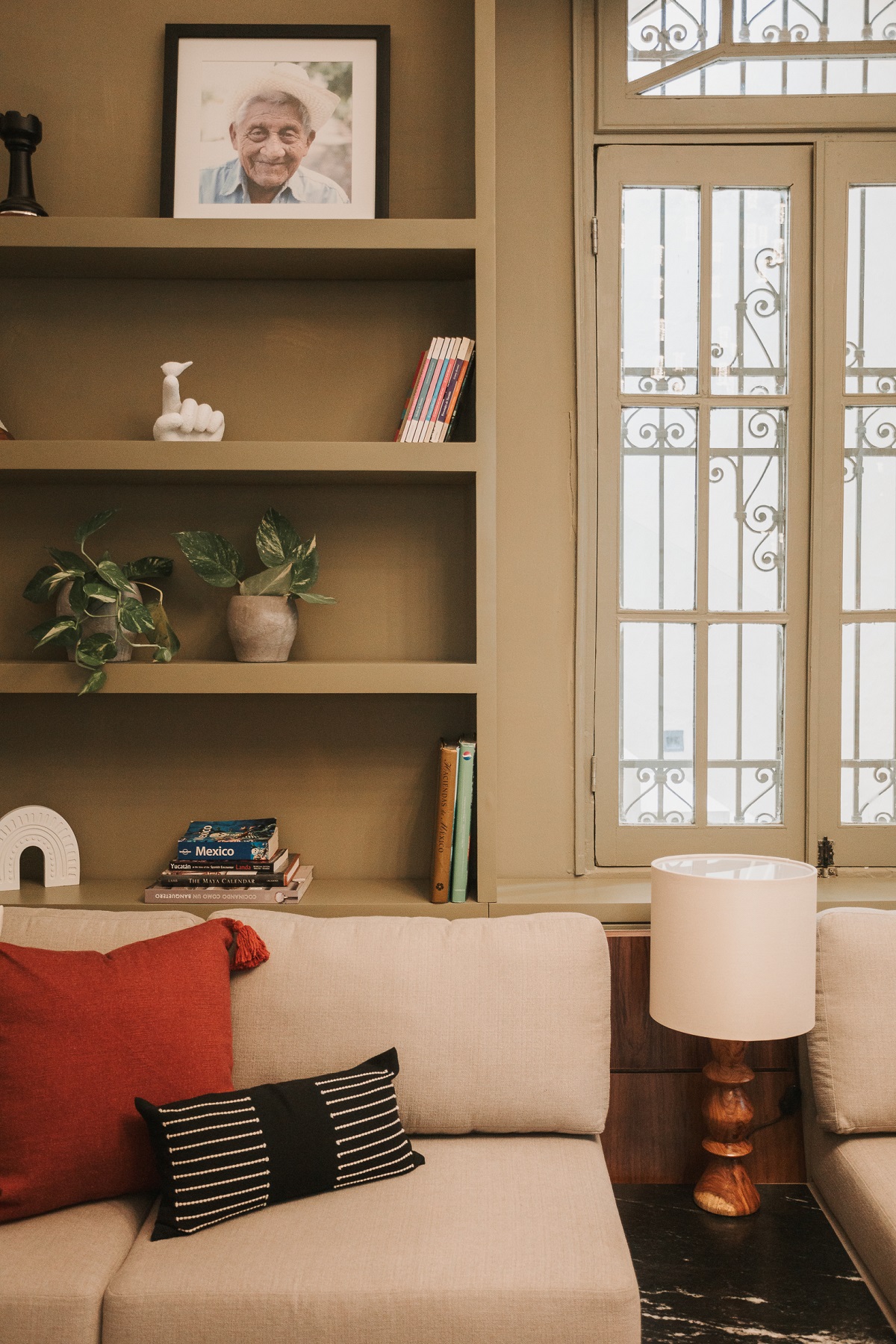 couch and cushions in front of shelves with art in Kahal