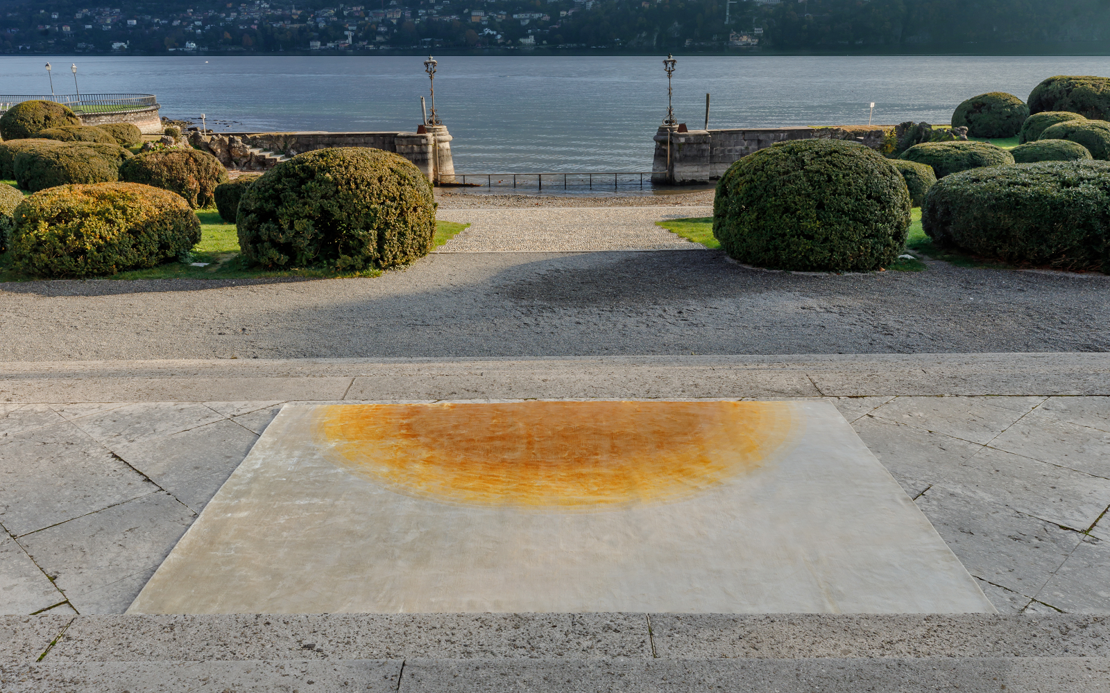 carpet with cream and orange abstract design on paving next to a lake