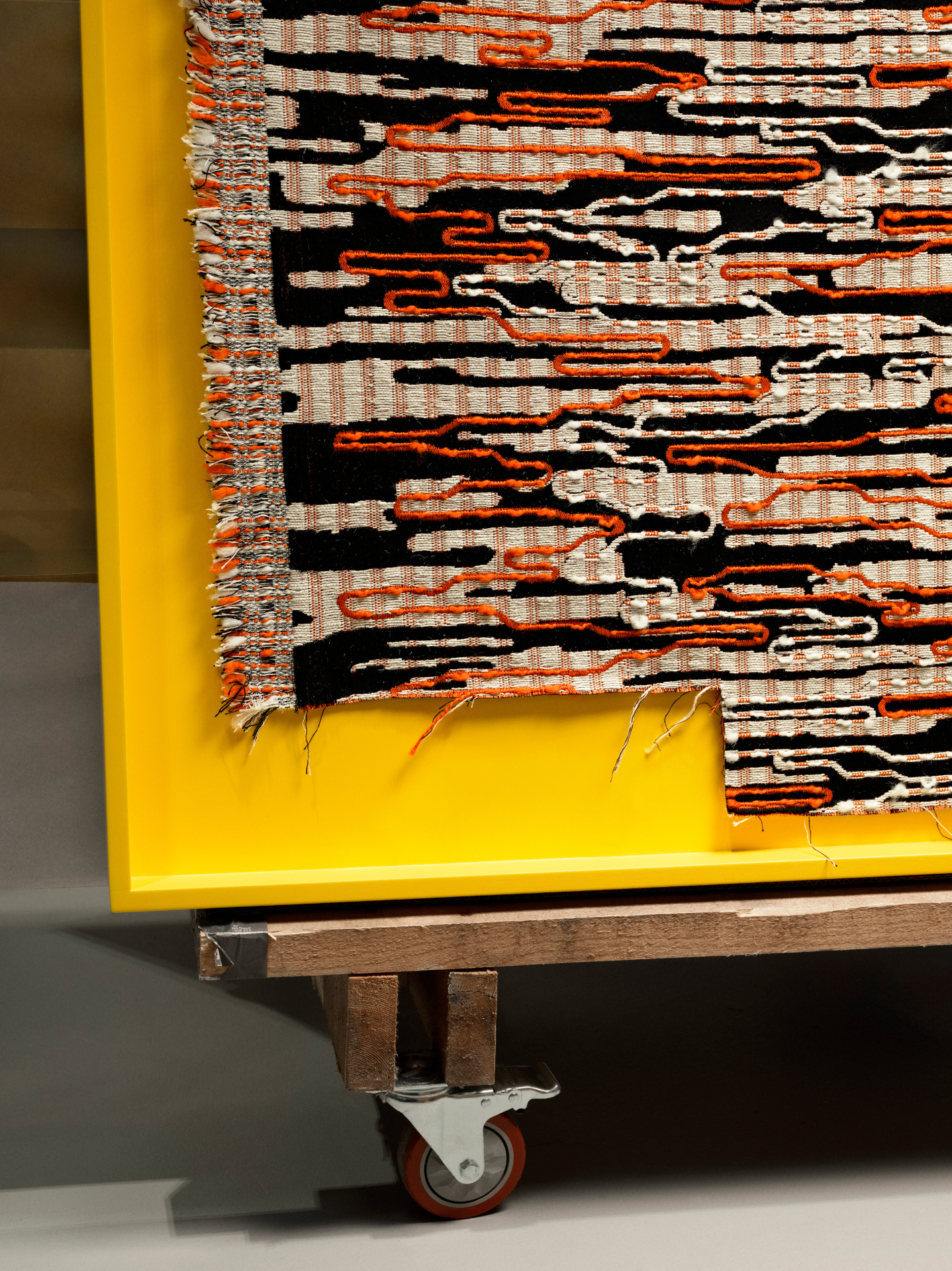 Woven textile set against yellow backdrop on wheels