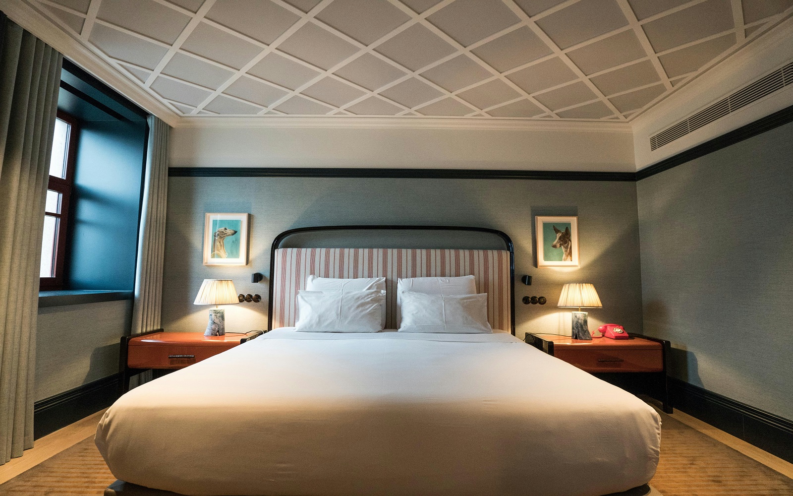 double bed in hotel guestroom with bed side lights lit up on either side