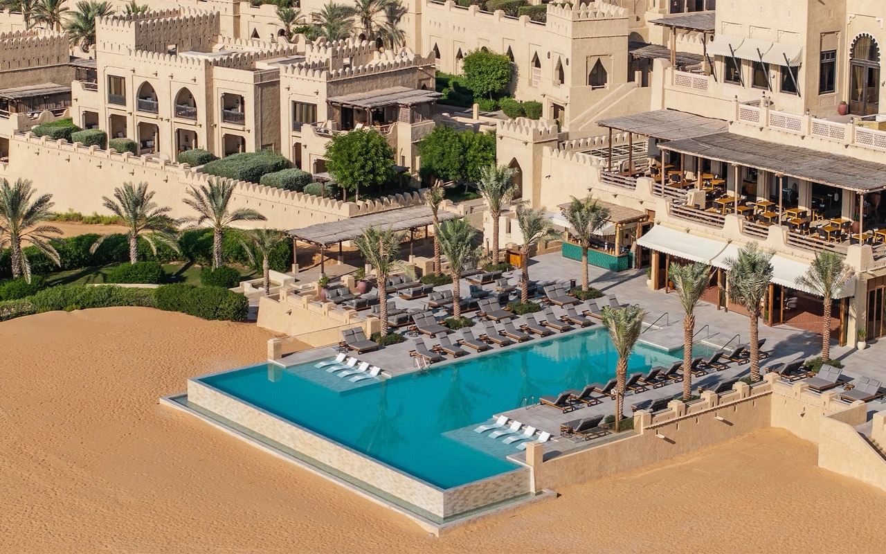 Shot from the air of infinity pool surrounded by SANIPEX outdoor furniture, at the Qasr Al Sarab